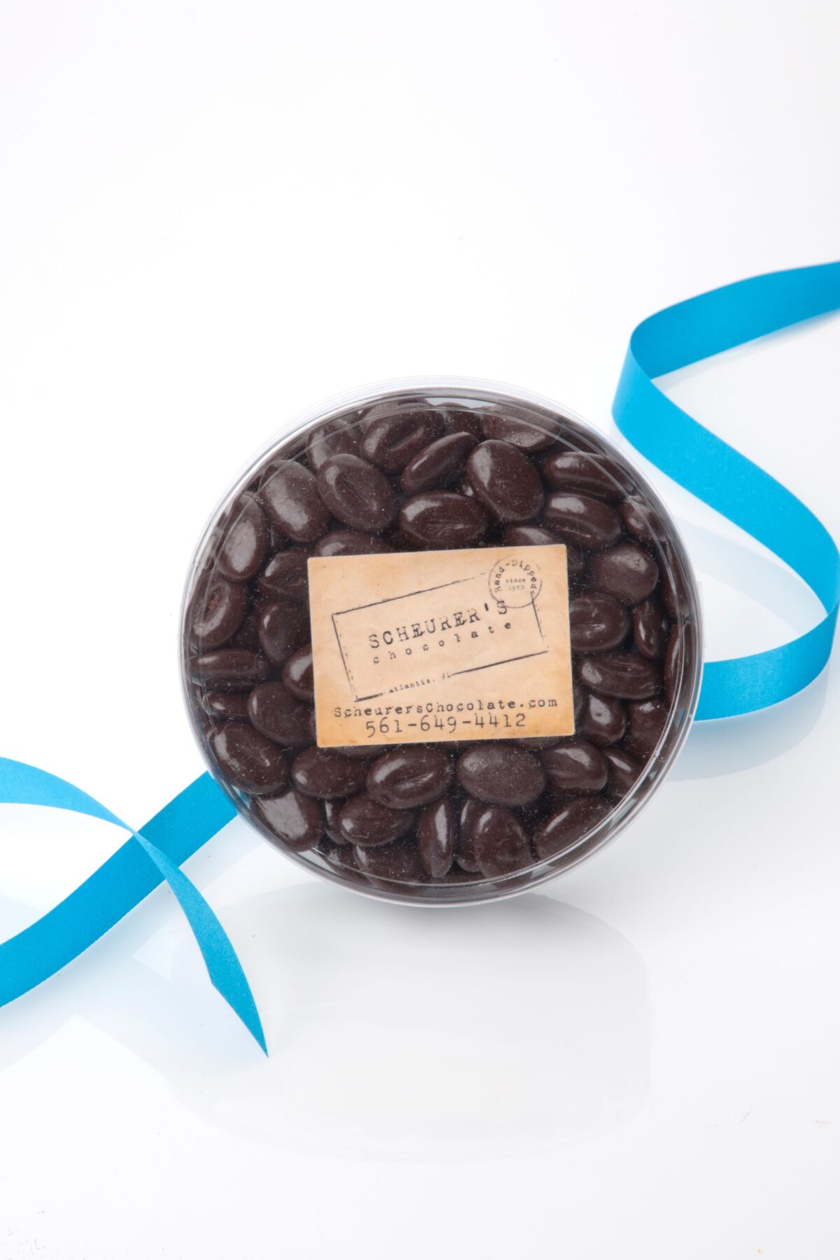 Round container filled with dark chocolates and a blue ribbon.